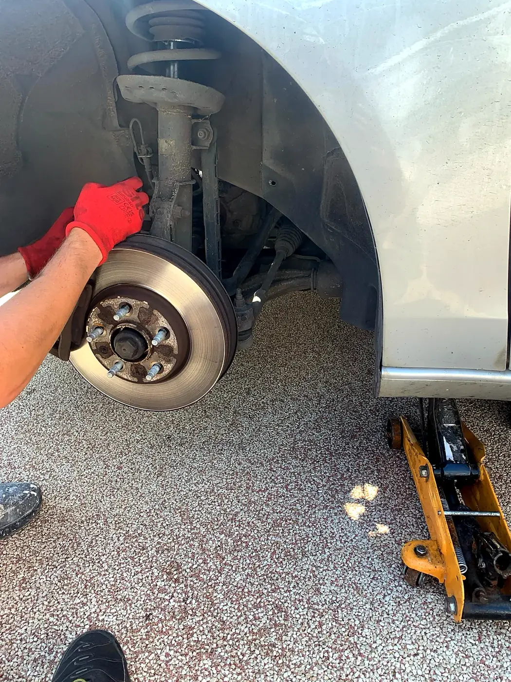 Mechanic fitting front suspension and hub on a silver car