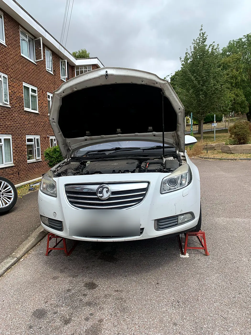 Vauxhall Insignia on axle stands for a mobile service outside a block of flats